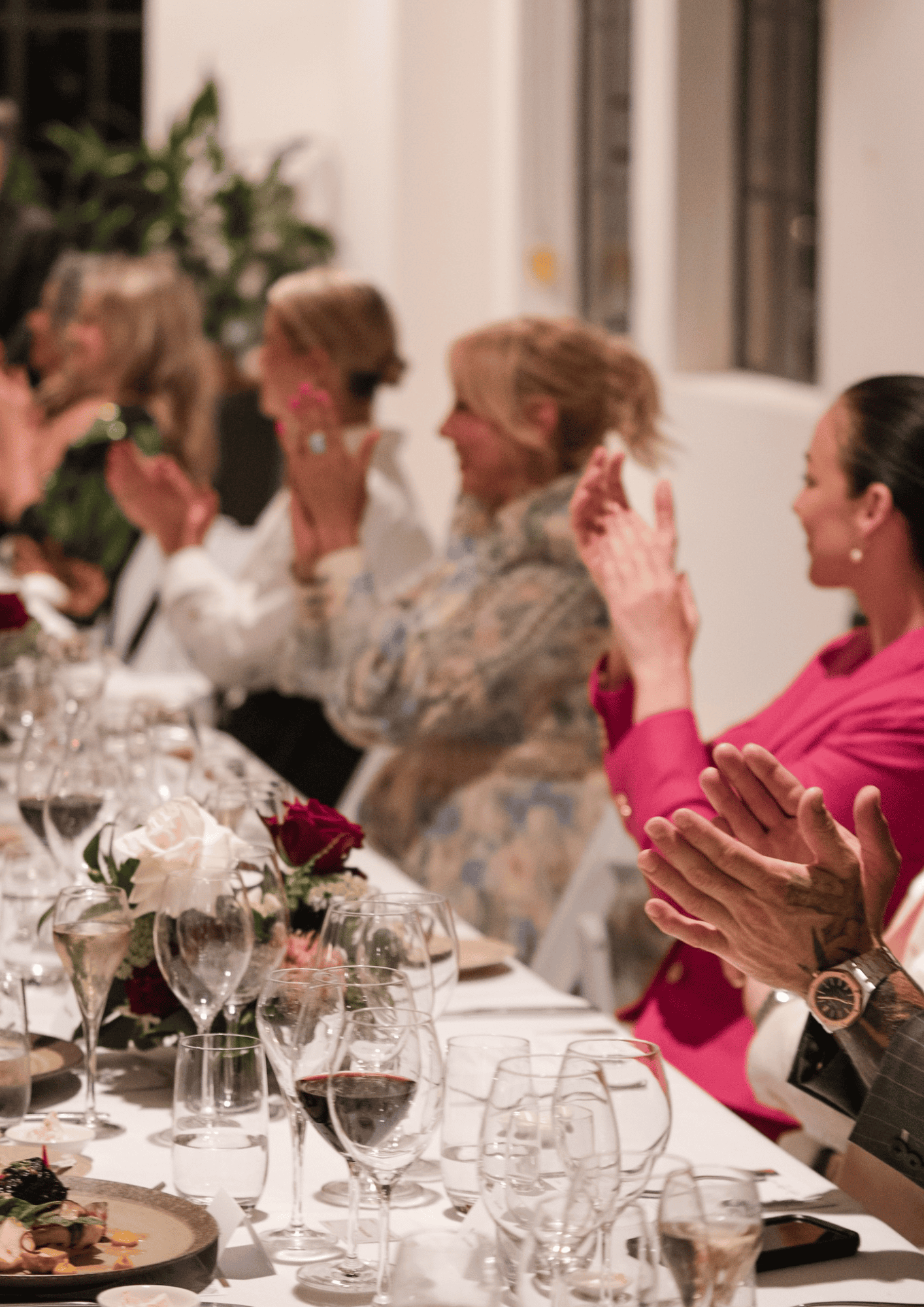 people sitting at a long dining table clapping at an event organised by lo key agency